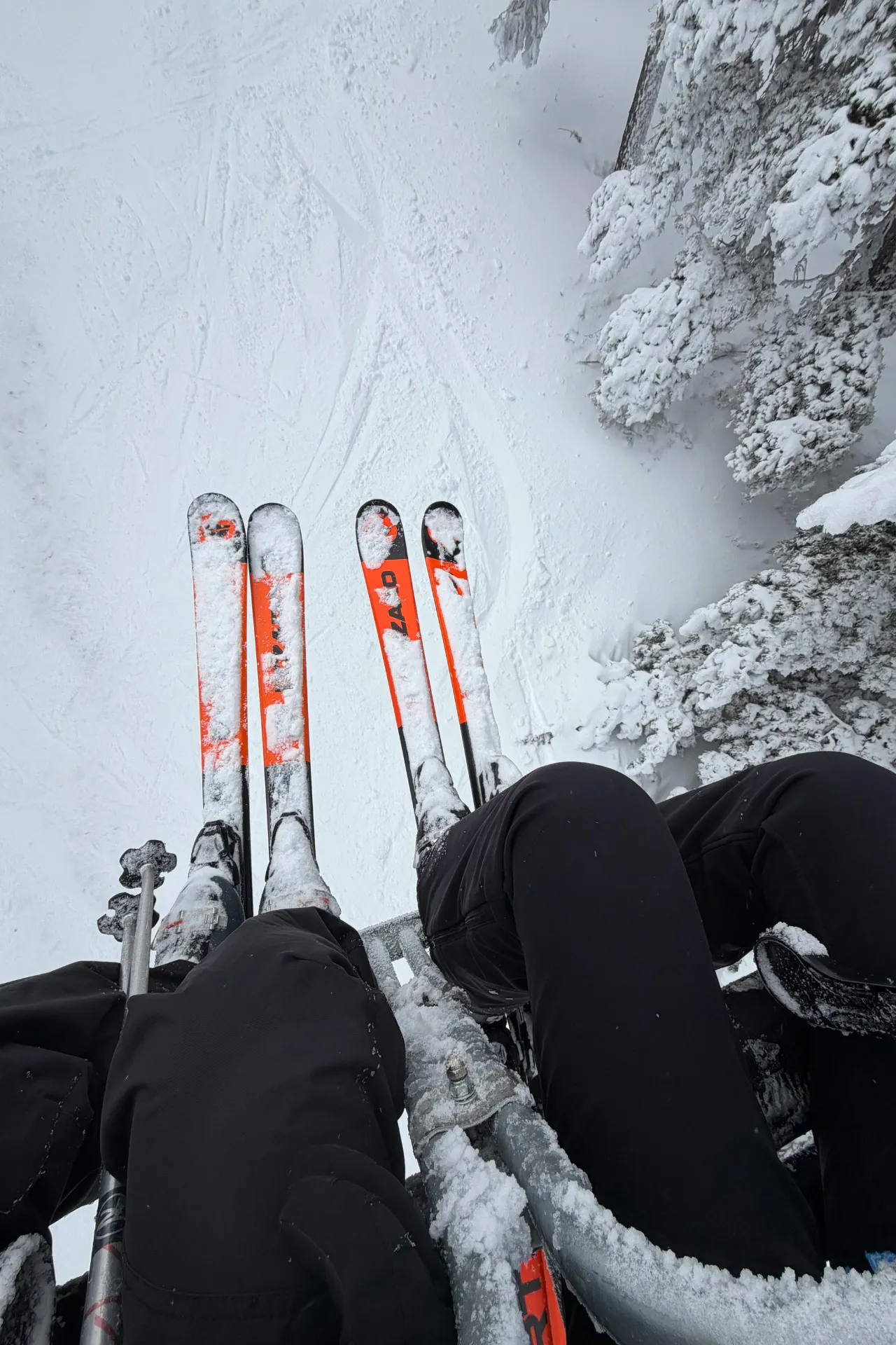 Twee skiërs die in een skilift zitten waarvan je de benen ziet hangen.