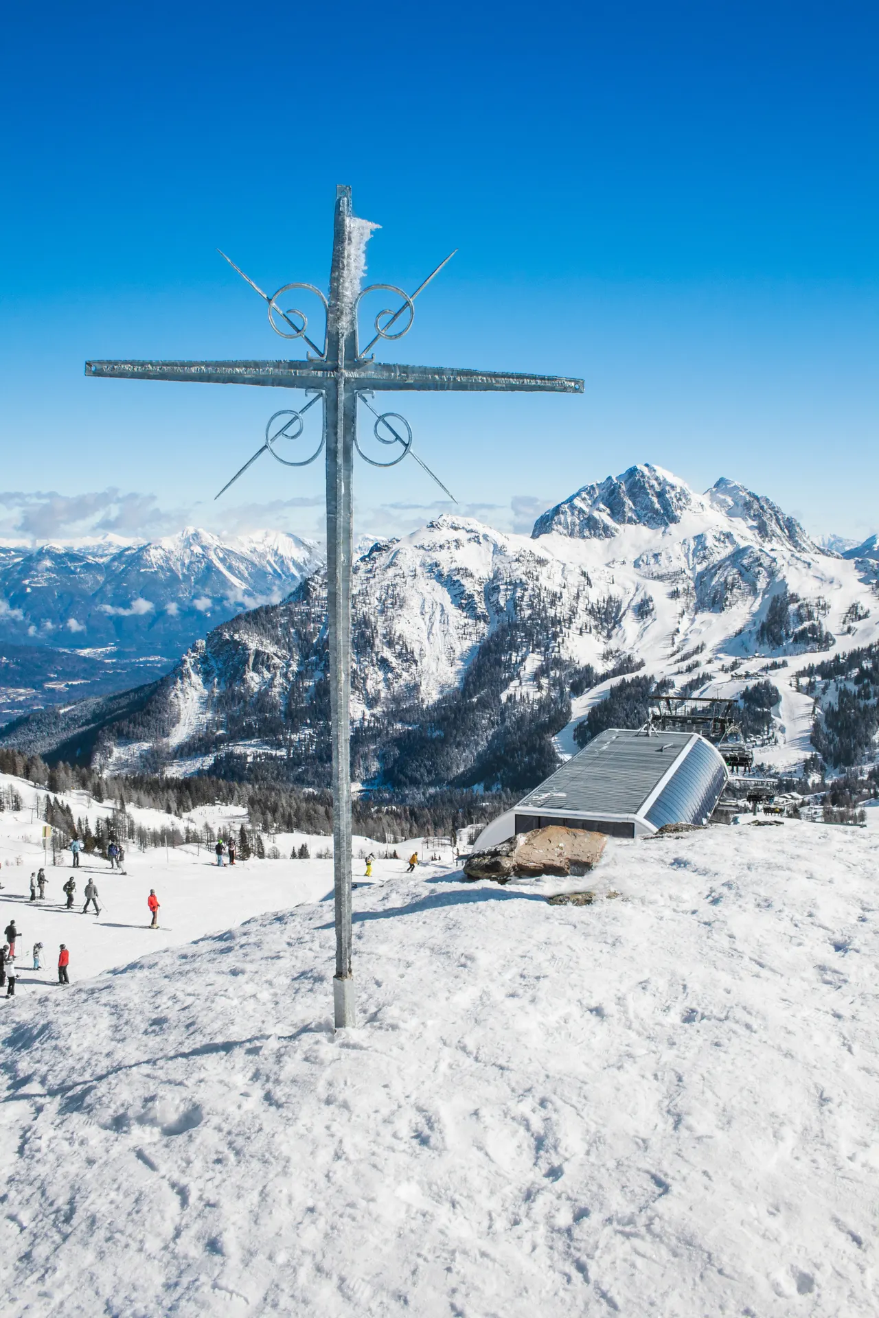 Kruis op de berg met onderaan skiërs