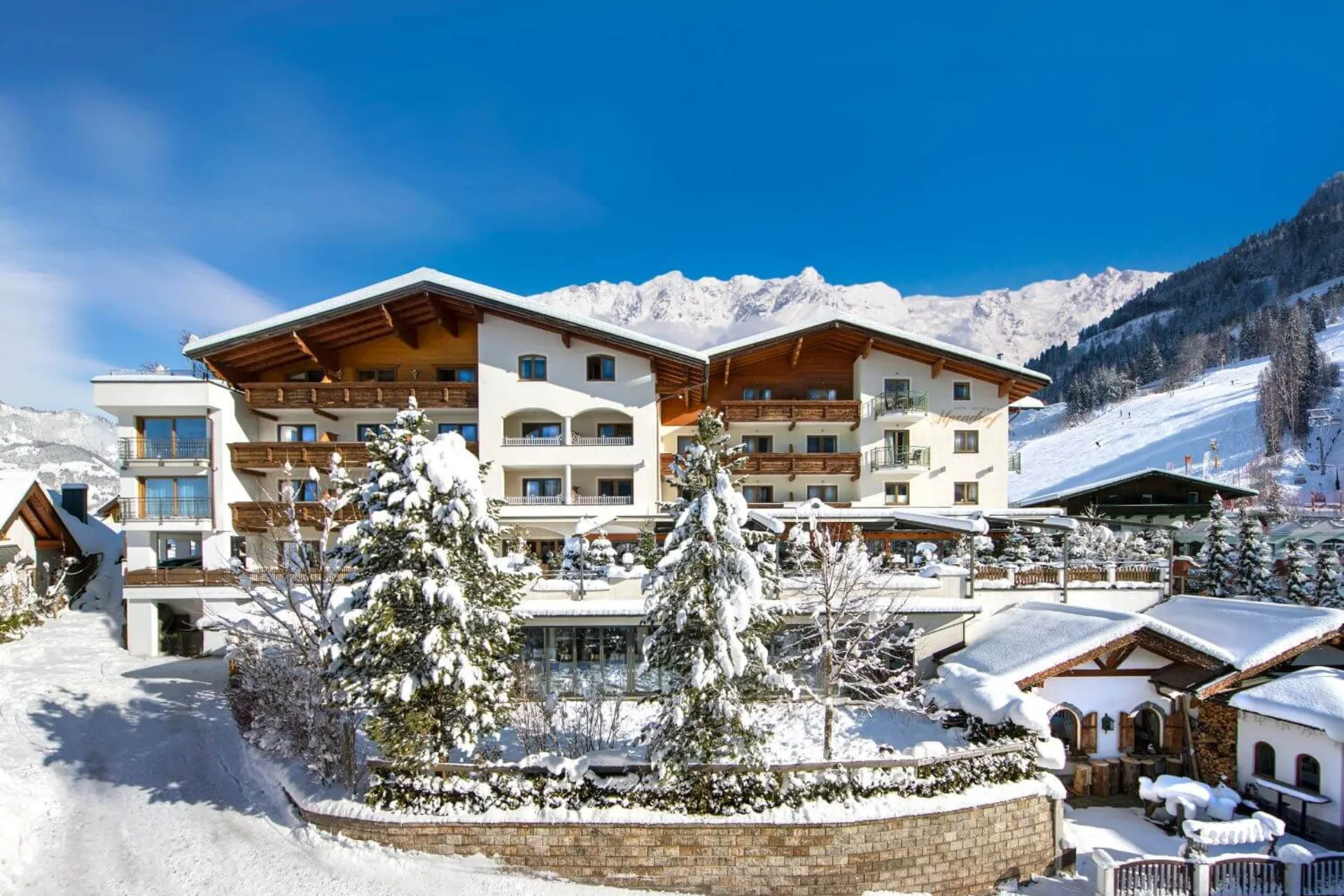 Het vooraanzicht van Hotel Alpendorf in Oostenrijk in de sneeuw.