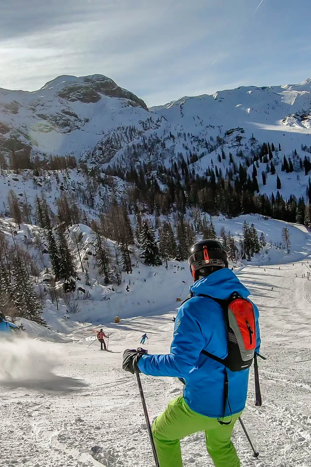 Een skiër p[ de berg die naar onder kijkt voordat hij de afdaling inzet