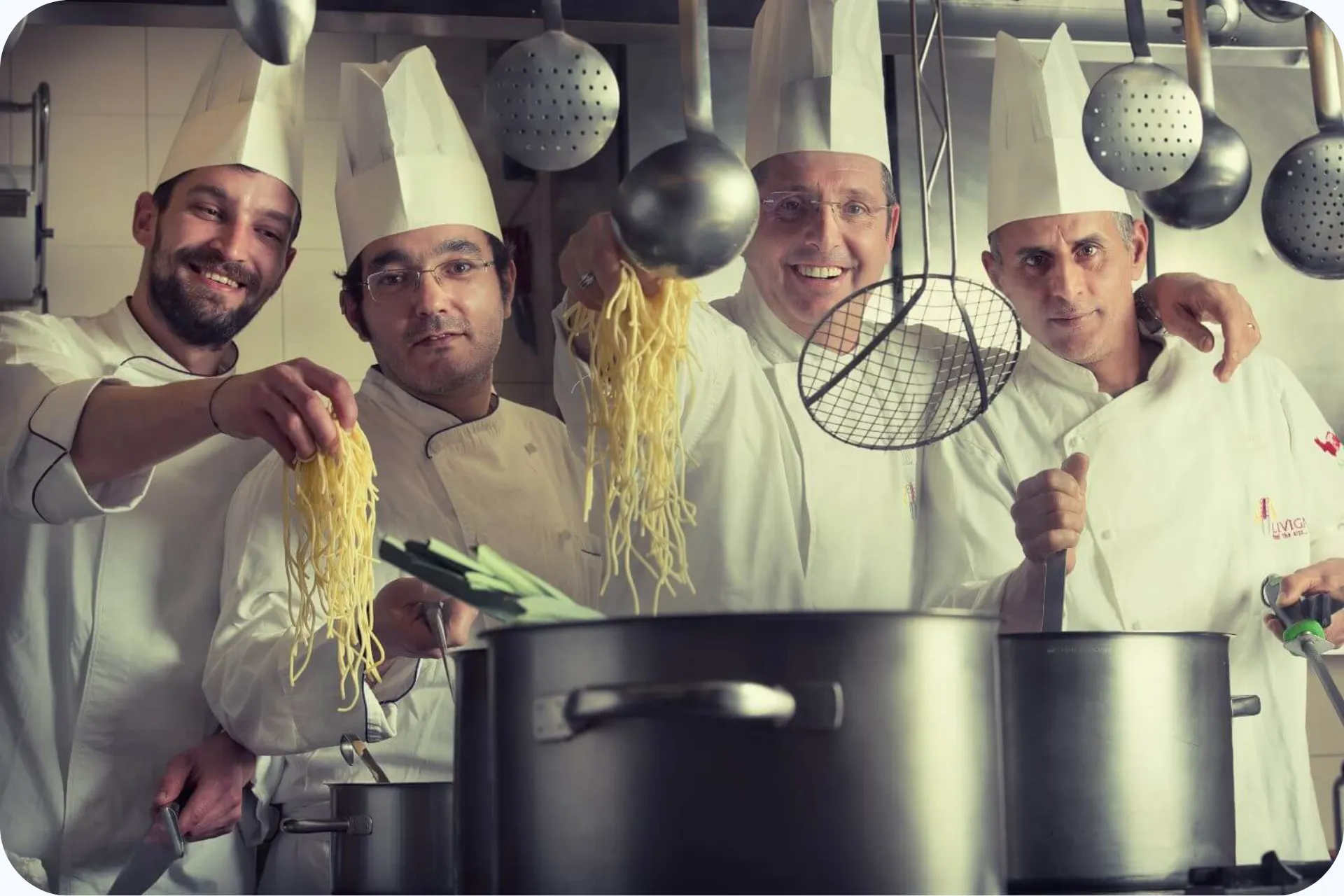 Keukenpersoneel die posseert met pannen pasta.