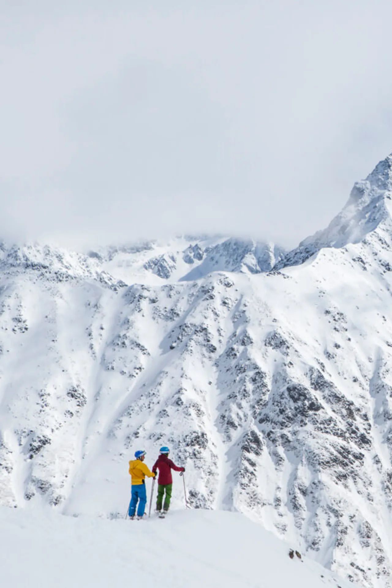 Twee skiërs die op de berg uitkijken over een uitzicht