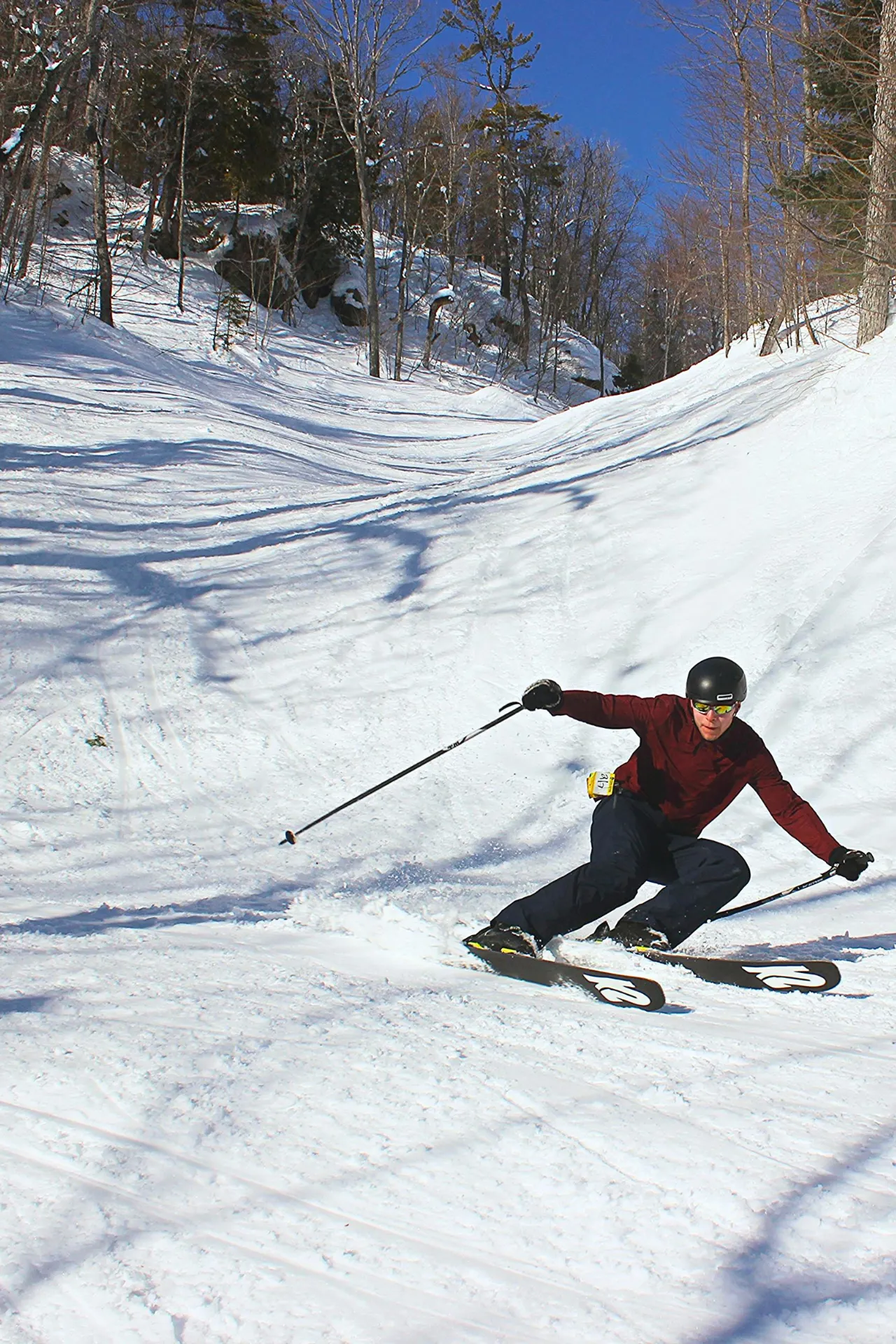 Een skiër op een piste tussen de bomen.