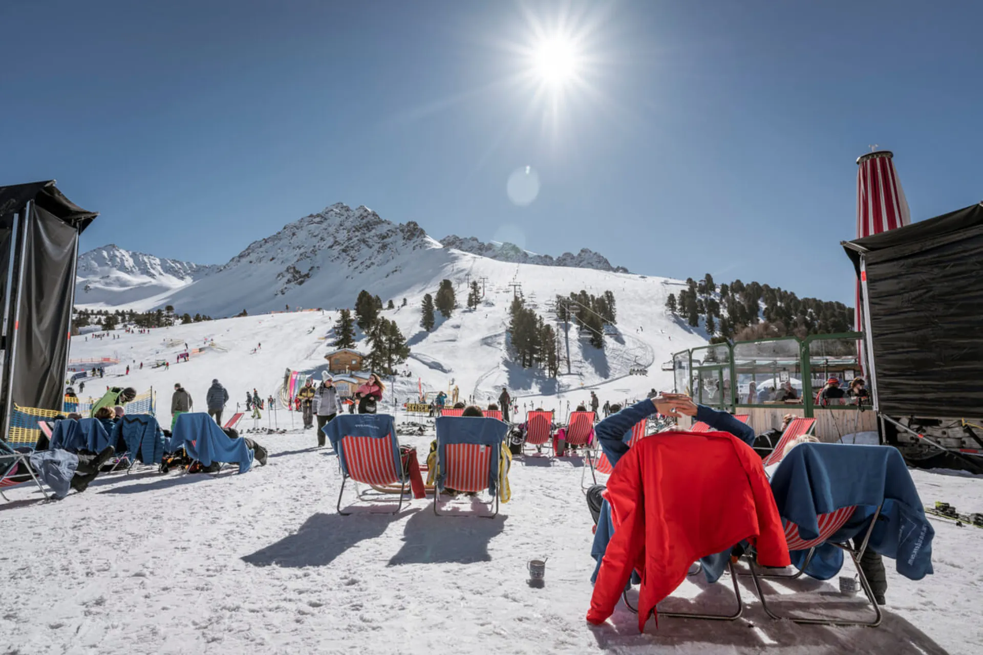 Skiërs die op bedjes in de zon rusten onderaan de piste.
