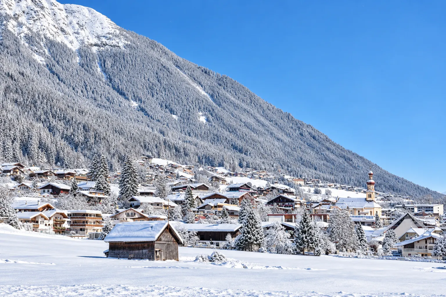 Winterlandschap van Fulpmes in het Stubaital met besneeuwde huizen, kerk en bergen.