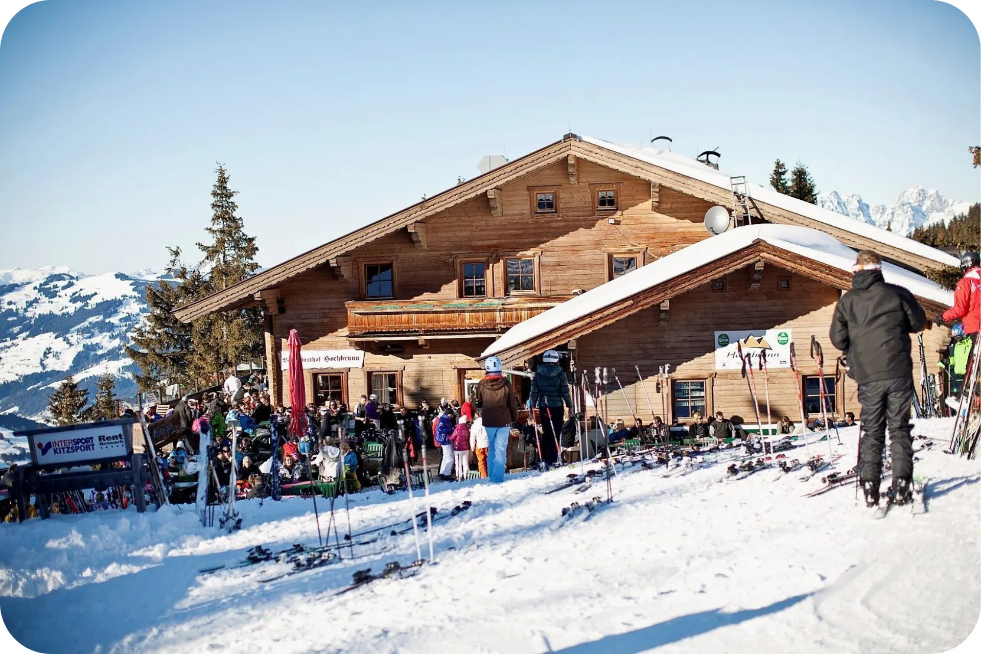 Een skihut waar veel skiërs buiten zitten in het zonnetje.