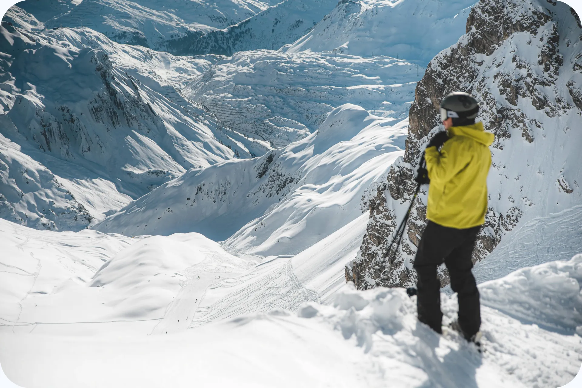 Man in gele ski jas, klaar voor de afdaling naar beneden.