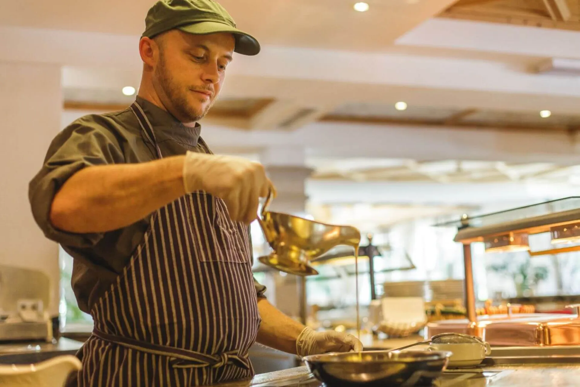 Een kok van hotel Gaspingerhof die bezig is met  een sausje bij een gerecht te doen tijdens het koken.