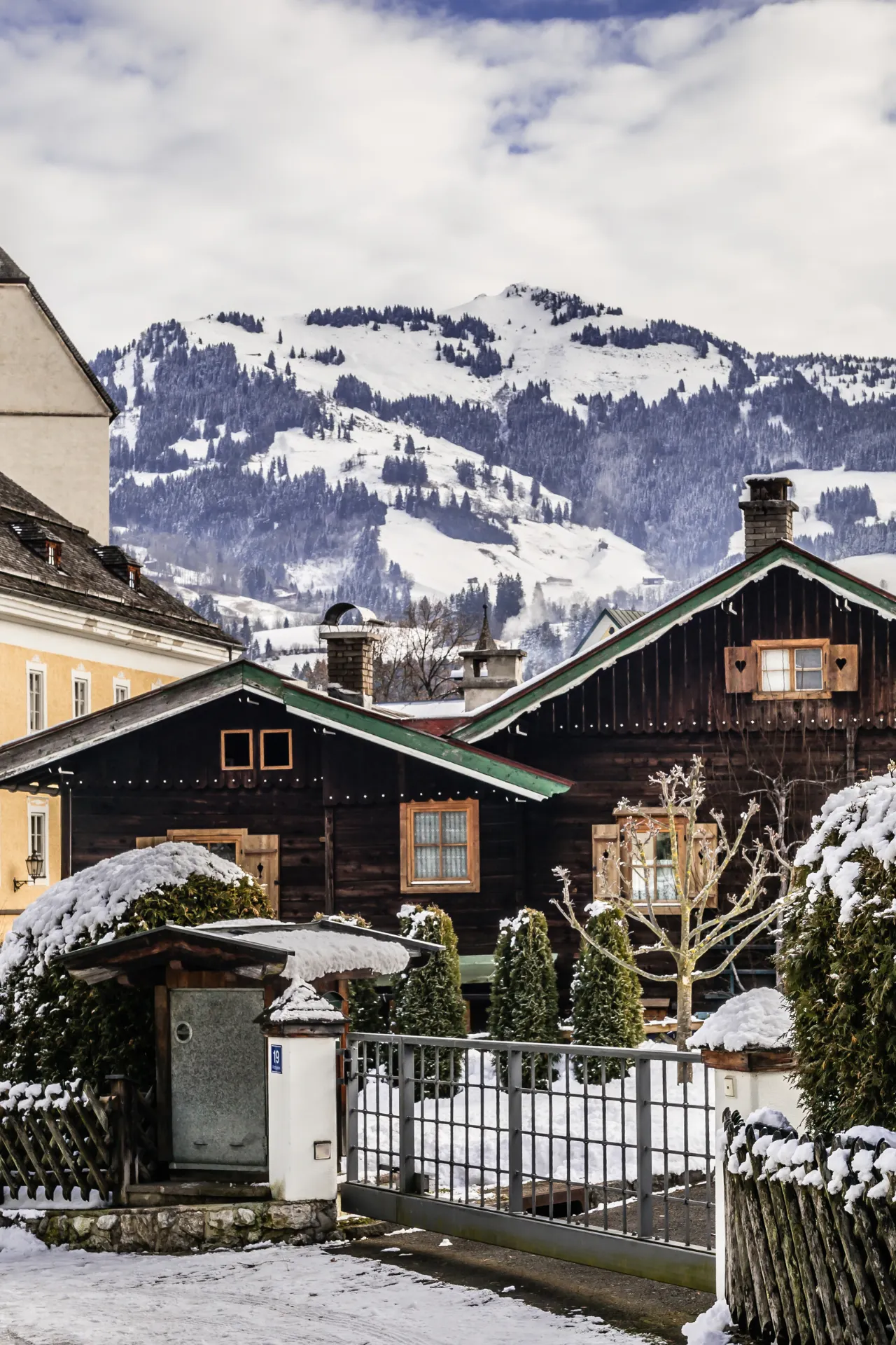 Besneeuwd houten huis met op de achtergrond de bergen in Kitzbühel