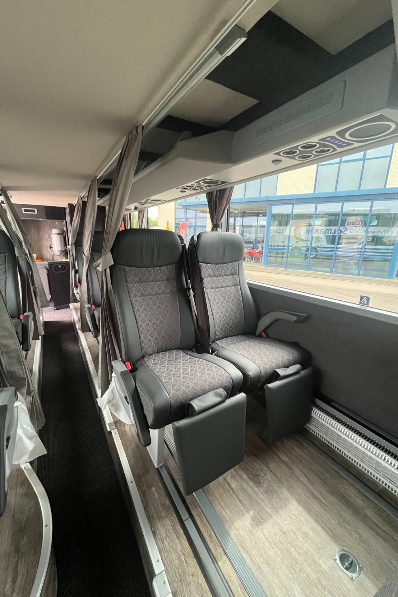 twee stoelen naast elkaar in een Premium Class bus, waar duidelijk de beenruimte op te zien is.