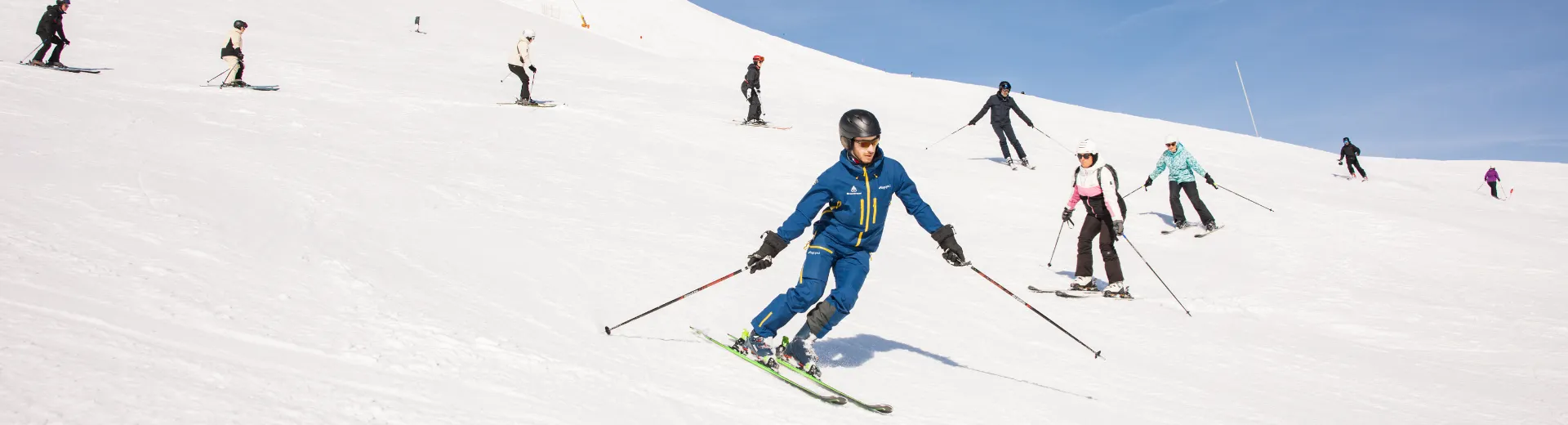 Groep mensen achter een skibegeleider aan.