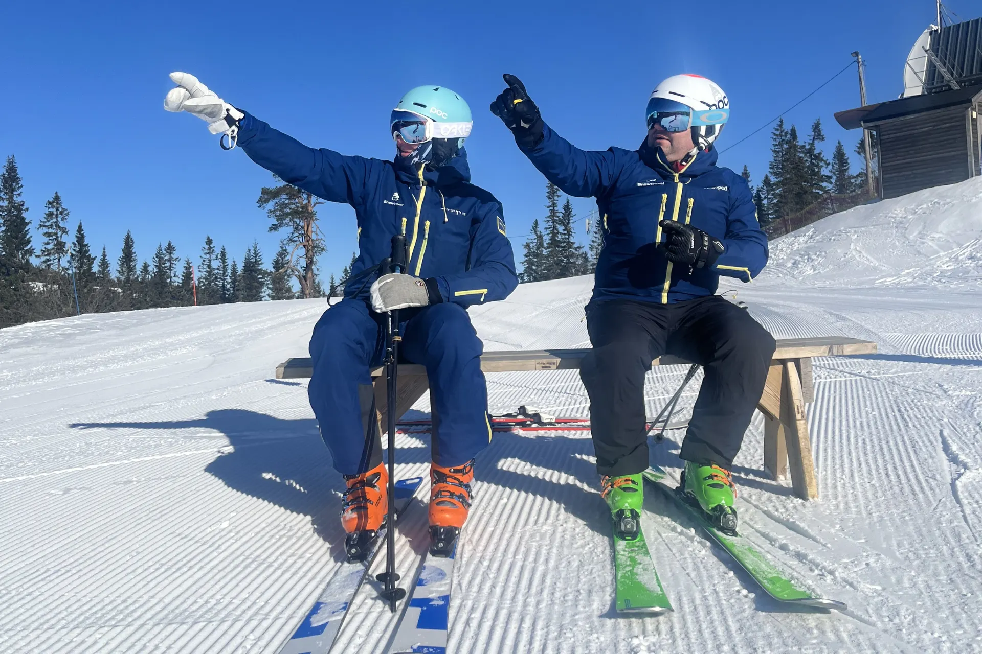 2 skimonitoren van Snowtravel op een bankje wijzend naar de lucht.
