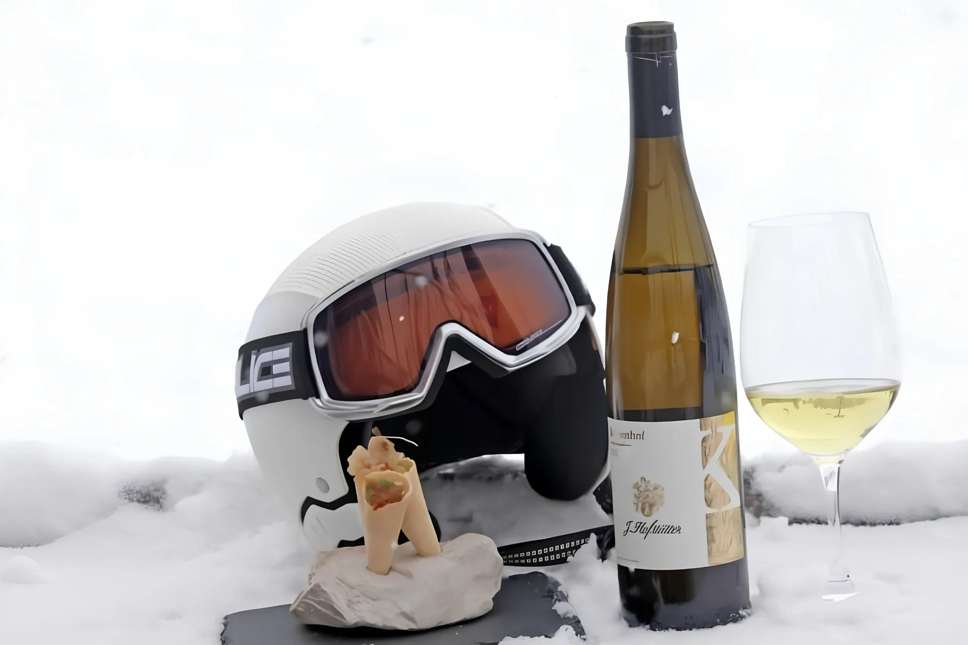 Skihelm met een fles witte wijn en een versnapering.