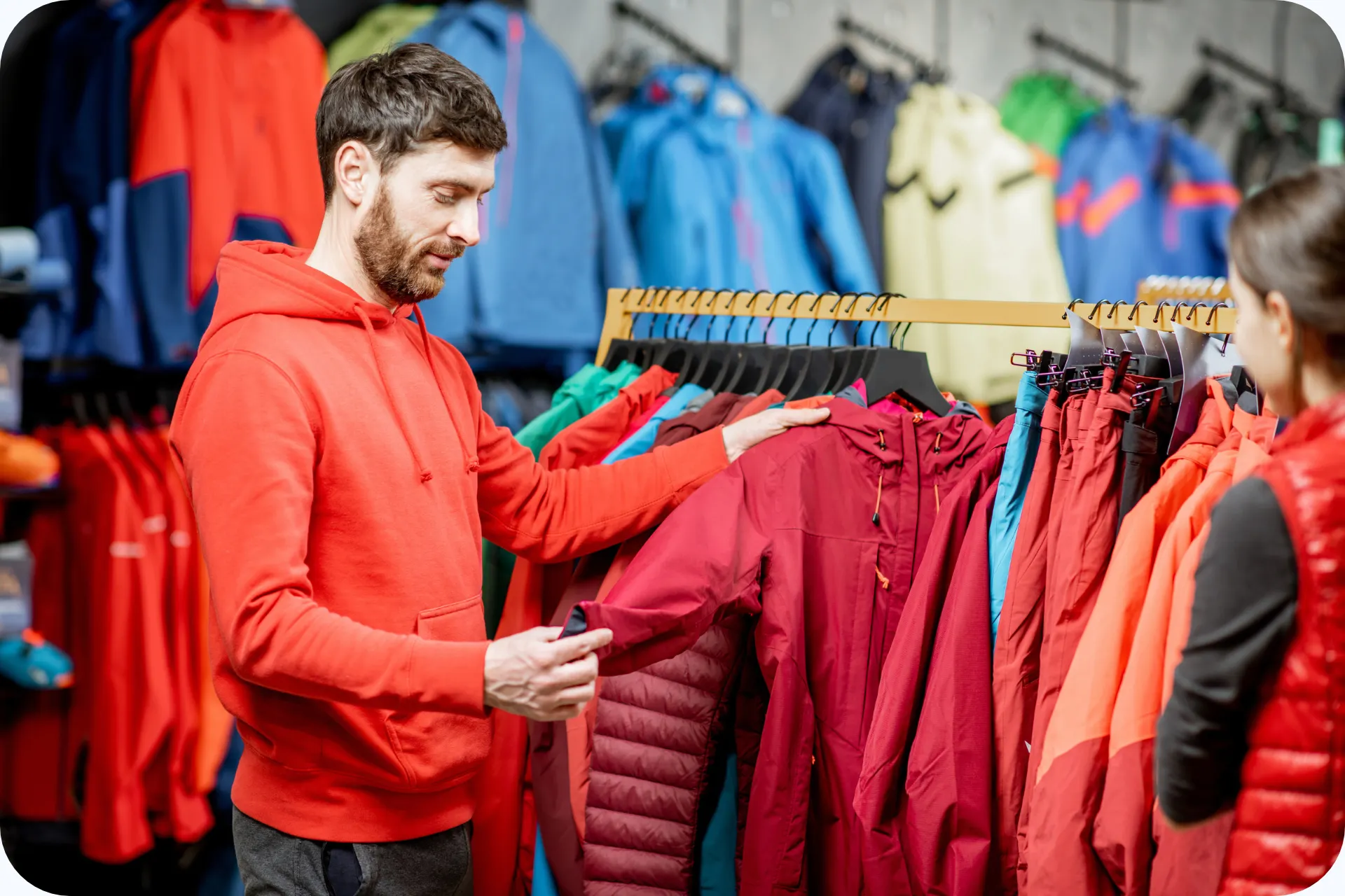 Een wintersporter bekijkt een ski jas in een winkel met een ruim aanbod aan kleurrijke wintersportkleding.