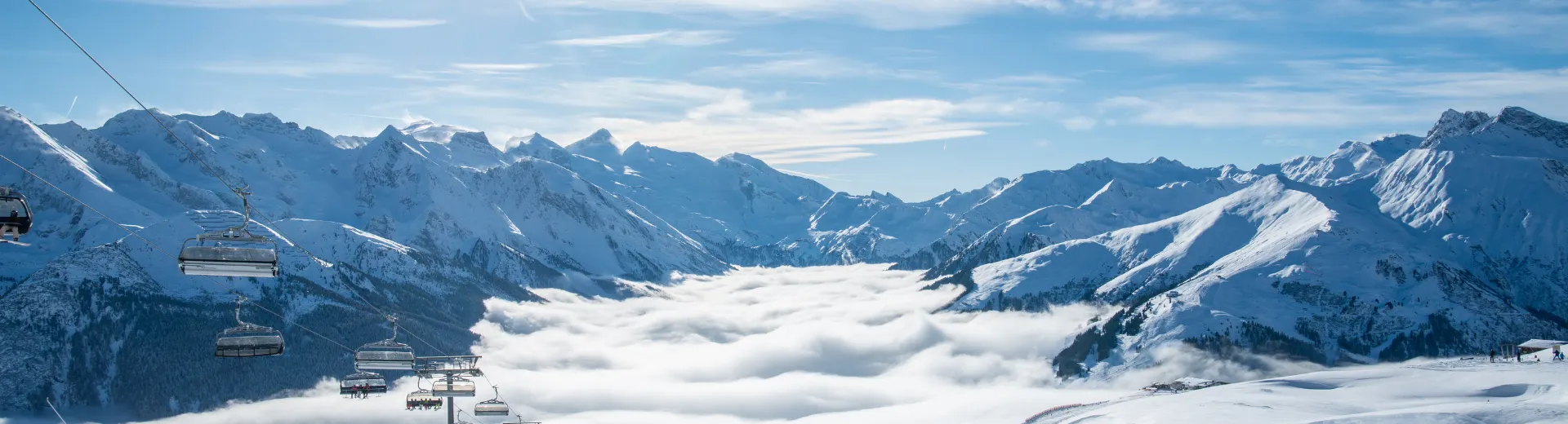 Links een skilift met uitzicht op de bergen en onder de wolken te zien zijn. Skilift in de bergen boven de wolken.