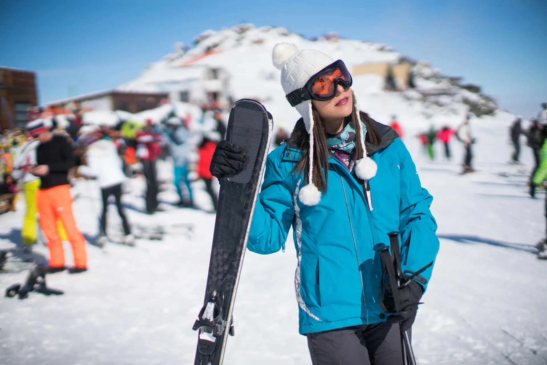Vrouw lachend met haar snowboard vast op de piste.
