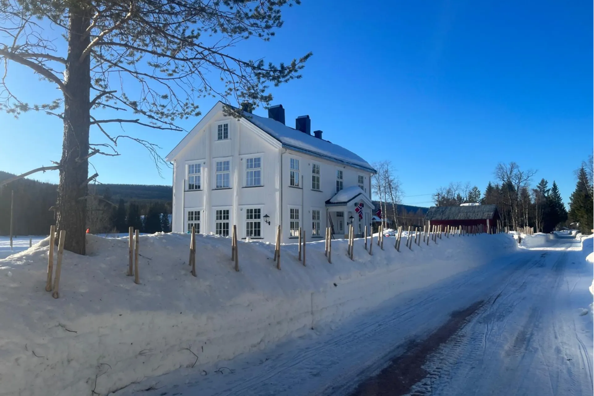 Afbeelding van een huis in Noorwegen met een blauwe lucht in een sneeuwrijke omgeving.