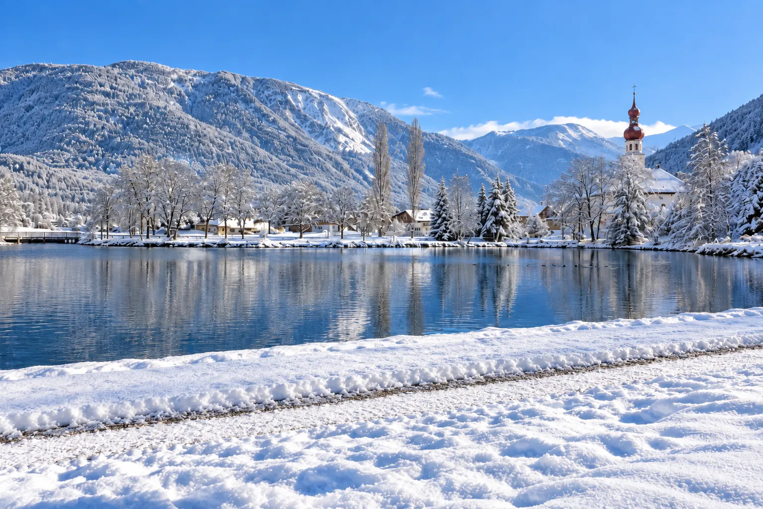 Winterlandschap in Nassereith met besneeuwde bergen, meer en dorpskerk in Tirol