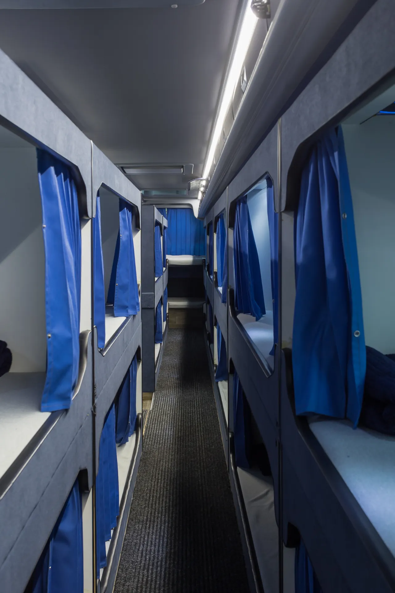 De binnenkant van het bovendek van een dream class bus met het gangpad in het midden en aan de zijkant de bedden